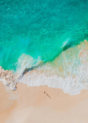 Aerial view of a beach with gentle waves and white sand in a tropical wonderland
