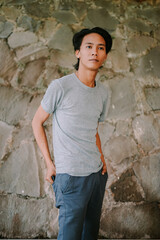 Southeast Asian man pulling a wallet from his pants pocket with a focused expression