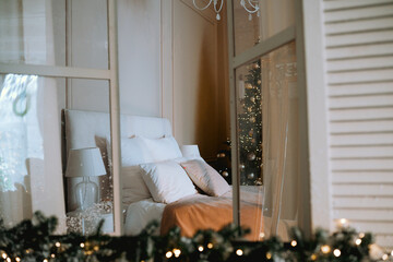 Cozy bedroom with elegant decor and holiday tree visible through window