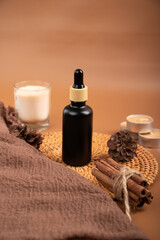 Black Dropper Bottle with Candle and Cinnamon on Woven Mat for Spa and Skincare