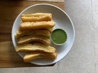 Churos with matcha sauce served on a white plate