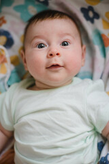 Portrait of a newborn baby. He looks at the camera and smiles. 3 months