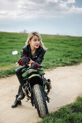 Obraz premium Woman in Leather Outfit Sitting on Motorcycle. Confident woman in leather pants and jacket sitting on a motorcycle. Ideal for themes of adventure, fashion, or biker lifestyle. Captures a bold.