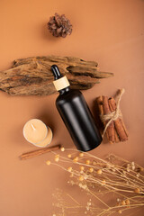 Aromatherapy Setup with Black Dropper Bottle, Candles, Cinnamon Sticks, and Reed Diffuser on Earthy Background