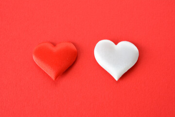 red and white silk hearts isolated on red background close up