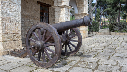 A fortress cast-iron cannon in an ancient fortress. Ancient weapons that fired cast-iron balls. Smooth bore cast iron cannon mounted on a wooden carriage.