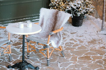 Cozy winter patio with a small table and mugs in a snowy setting