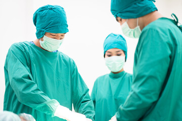 Close-up of professional surgical team in green scrubs performing precise operation on patient heart failure in operating room. Emphasis on teamwork, and healthcare in sterile medical hospital