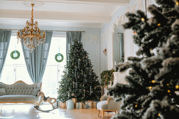 Elegant Christmas living room decorated with trees and wreaths in daylight