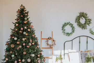 Cozy bedroom with a beautifully decorated Christmas tree and wreaths