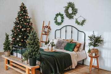 Cozy bedroom decorated for Christmas with a festive tree and greenery accents