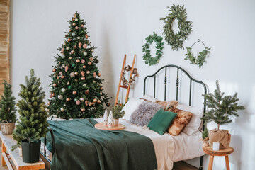 Cozy bedroom decorated for the holidays with a Christmas tree and greenery