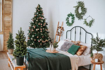 Cozy bedroom decorated for Christmas with a tree and festive greenery