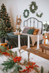 Cozy holiday bedroom with decorations, festive tree, and candles in winter