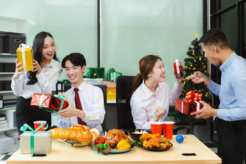 Successful business team, young people, celebrating together and gift exchange at Merry Christmas and New Year in the workplace.