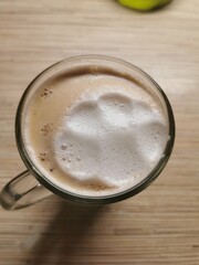 Glass mug of coffee with paw print foam on wooden table
