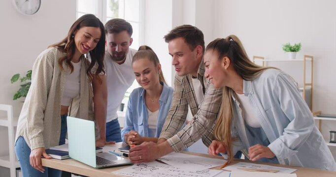 Young team of office workers looking at laptop and rejoicing in victory. Concept Collaborative team meeting, employees together, executive staff, successful professional, positive relationship