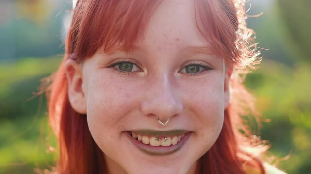 Young beautiful smiling girl with piercing on her face in fashionable clothes. Carefree woman smiling on the street on a sunny day. Positive teenager on the street.
