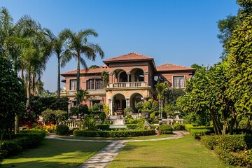 Fototapeta premium An opulent estate nestled among verdant gardens epitomizes sophistication and grandeur beneath a pristine azure sky.