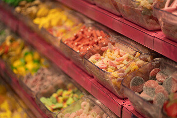 An assortment of colourful candies arranged neatly at a market, offering a tempting selection of sugary delights in every shade. The bright colours of the candy make it an irresistible sight.