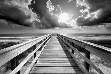 Dramatic black and white boardwalk leading to the beach under a moody sky.
