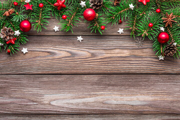 Christmas background with fir tree branches, red decorations and pine cones on rustic wooden table. Flat lay. Happy New Year and winter holidays layout. Top view with copy space