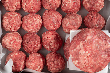Semi finished patties and meatballs in a metal tray