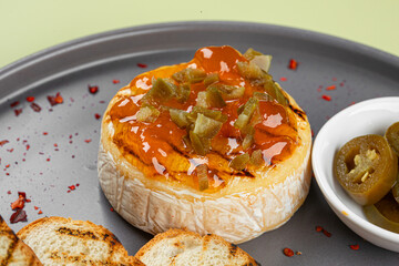 Portion of baked brie cheese with jalapeno pepper and toast