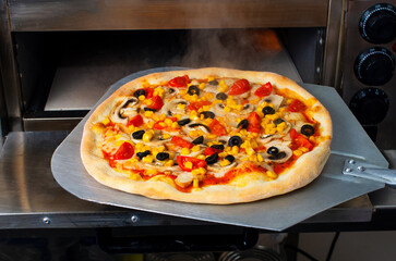 Pizza cooked, steamed, on a shovel in an electric oven