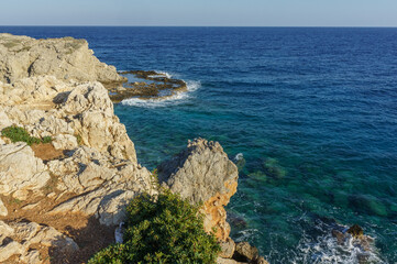 Serene coastal view from rocky cliffs overlooking the clear blue sea during a bright sunny day. - Powered by Adobe