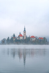 Late autumn on Lake Bled. Morning misty landscape. Travel in Slovenia. Picturesque church on the island on Lake Bled in autumn morning