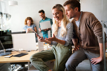 Two young businesspeople using a digital tablet while standing in a boardroom.