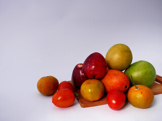 
Tropical fruit to meet your body's vitamin needs; a collection of fruit around a wooden cutting board with a white background