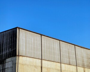 Fototapeta premium Aluminum corrugated industrial warehouse metal wall surface building on against blue sky background