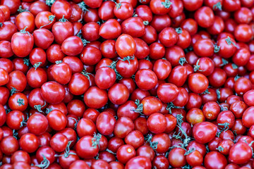 background of ripe red cherry tomatoes for sale at the market. Selective focus.