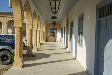 Obraz premium A sunlit corridor framed by classic arches in an old stone building during a serene afternoon.