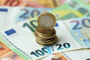 One euro coin lies on huge amount of different euro dollars banknotes