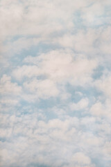 Vintage romantic sky with sweet clouds vertical background. Light blue sky with cotton white clouds poster in a tender 70s mood. Altocumulus.