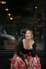 woman sitting and laughing in front of the big mirror of the cofee shop.