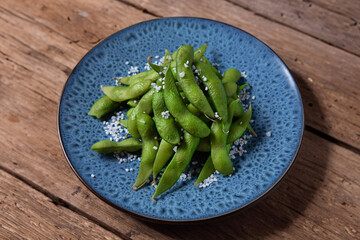 Edamame beans served on plate on wooden background 