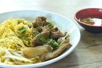 dry boiled yellow egg noodles with braised beef in Chinese  herb on plate dipping spicy chili sauce