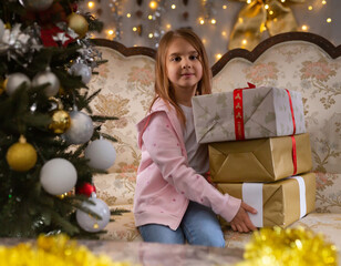 Little girl holding gifts in Christmas interior