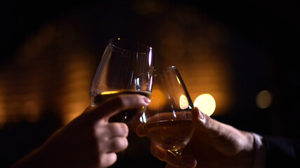 Clinking Glasses with White Wine in a Dimly Lit Atmosphere