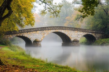 Fototapeta premium Bridges Over a Foggy River: A historic bridge arching over a slow-moving river