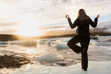 Mujer haciendo yoga en laguna glaciar, Islandia.