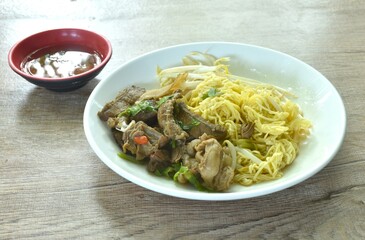 dry boiled yellow egg noodles with braised beef in Chinese  herb on plate dipping spicy chili sauce
