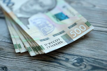 Many five hundred hryvnia money bills lies on wooden background. Ukrainian national currency close...