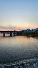 서울의 한강에서 노을지는 하늘과 불빛이 반짝이는 교량이 있는 도시 경관