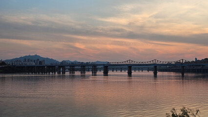 Fototapeta premium 서울의 한강에서 노을지는 하늘과 불빛이 반짝이는 교량이 있는 도시 경관