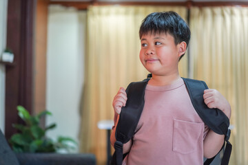 Young asian boy with backpack ready for school standing with determined expression, back to school preparation, childhood education journey, elementary student to learn, portrait of happy schoolboy